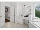 Bright bathroom includes tiled floors, dual sinks, and soaking tub with large window overlooking trees at 6219 Creekstone Path, Cumming, GA 30041