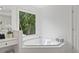 Bright bathroom featuring a large window over the tub, vanity, and storage baskets for added convenience at 6219 Creekstone Path, Cumming, GA 30041