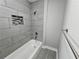 Modern bathroom features a bathtub with gray tile surround, a shower niche, and sleek fixtures at 1753 Cahoon Sw St, Atlanta, GA 30310