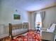 Cozy Bedroom featuring a crib, soft lighting, a chair, and a window with soft drapes for a soothing atmosphere at 2210 Cumberland Se Ct, Smyrna, GA 30080