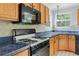 Close-up on range cooktop featuring wood cabinetry, blue countertops, unique backsplash, and black appliances at 4001 English Valley Dr, Ellenwood, GA 30294