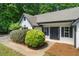 Inviting front porch of a white home featuring manicured bushes, black shutters, and a black front door at 545 Willow Creek Dr, Temple, GA 30179
