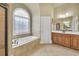 Spacious bathroom with tiled flooring, soaking tub under decorative window, and wood vanity at 2740 Heritage Bend Sw Ct, Grayson, GA 30017