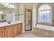 Bright bathroom with double vanity, separate shower, and soaking tub beneath a decorative arched window at 2740 Heritage Bend Sw Ct, Grayson, GA 30017