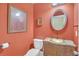 A half bathroom features an ornate vanity, mirror, lighting, and rust-colored walls at 2740 Heritage Bend Sw Ct, Grayson, GA 30017