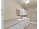 A laundry room has a sink, counter, cabinets, shelving and a washer and dryer on tile flooring at 2740 Heritage Bend Sw Ct, Grayson, GA 30017