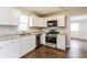 Well-lit kitchen with white cabinets, stainless steel appliances, and dark wood floors at 4820 Oak Grove Dr, Cumming, GA 30040