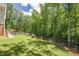 Spacious backyard with lush lawn and wooded view, enhanced by a black fence at 124 White Oak Trl, Cumming, GA 30028