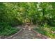 A charming swing framed by mature trees and lush landscaping in the private backyard retreat at 1679 Summit Place Way, Loganville, GA 30052