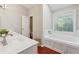 Bright bathroom with a tub next to the window and white vanity at 1679 Summit Place Way, Loganville, GA 30052