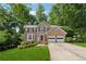 Charming two-story brick home featuring an attached two-car garage, manicured lawn, and mature trees at 1679 Summit Place Way, Loganville, GA 30052