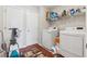 Functional laundry room with washer, dryer, storage shelves, and wood-look floors at 1679 Summit Place Way, Loganville, GA 30052