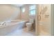 Bright bathroom featuring a tub, toilet, and glass-enclosed shower with decorative octagonal window at 3510 Eagle Landing Dr, Snellville, GA 30039