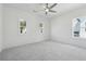 Bright bedroom featuring neutral carpet, two windows, ceiling fan, and light-colored walls at 784 Keystone Dr, Woodstock, GA 30188