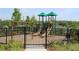 A playground features swings, slides, and a green shade cover inside of a black metal fence at 784 Keystone Dr, Woodstock, GA 30188