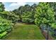 Spacious backyard with lush green grass, tall trees, and secured by a black iron fence at 1231 Ellington Ct, Cumming, GA 30041