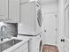 Bright laundry room features stacked washer and dryer and a utility sink at 1231 Ellington Ct, Cumming, GA 30041