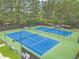 Aerial view of well-maintained tennis courts surrounded by lush greenery and tall trees at 1419 Gates Mill Walk, Lawrenceville, GA 30045