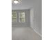 A brightly lit bedroom features a large window and neutral walls and floors at 6240 Vista Crossing Way, Cumming, GA 30028
