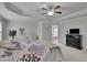Spacious bedroom featuring tray ceilings, a ceiling fan, plush carpet, and access to the ensuite bathroom at 6240 Vista Crossing Way, Cumming, GA 30028