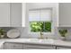 Close-up of a kitchen featuring white cabinets, stone countertops, and stainless fixtures at 1444 Merrifield Ln, Marietta, GA 30062