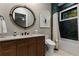 Elegant bathroom with dark wood vanity, quartz countertop, round mirror, and bathtub with dark tile surround at 3085 Lake Park Dr, Jonesboro, GA 30236