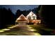 Nighttime exterior of a brick home with a two-car garage, manicured lawn, and accent lighting along the driveway at 5928 Edenfield Nw Dr, Acworth, GA 30101
