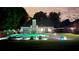 Backyard pool with in-pool seating, ample lounging area, and a covered gazebo, all brightly lit at night at 5928 Edenfield Nw Dr, Acworth, GA 30101
