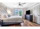 Cozy bedroom featuring hardwood floors, a ceiling fan, and a dresser with a TV, creating a relaxing retreat at 2510 Wood Creek Ct, Dacula, GA 30019
