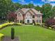 Stunning brick home with a manicured lawn, mature trees, and lush landscaping, showcasing curb appeal at 2510 Wood Creek Ct, Dacula, GA 30019