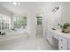 Bright bathroom featuring a soaking tub, large window, and double sink vanity with white cabinets at 4711 Oakleigh Manor Dr, Powder Springs, GA 30127