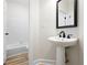 Powder room features a pedestal sink, modern fixtures and view of bathtub at 4711 Oakleigh Manor Dr, Powder Springs, GA 30127