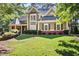 Charming two-story home featuring manicured lawn, brick accents, and complemented by mature trees at 4711 Oakleigh Manor Dr, Powder Springs, GA 30127