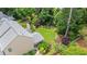 Aerial view of landscaped backyard, stone patio, mature trees, and well-manicured lawn at 8045 Depford Way, Cumming, GA 30041