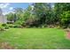 Lush backyard featuring a green lawn, mature trees and plants, and well-manicured landscaping at 8045 Depford Way, Cumming, GA 30041