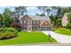 Traditional brick home featuring a well-manicured lawn, mature trees, and a two-car garage at 8045 Depford Way, Cumming, GA 30041
