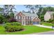 Traditional brick home boasting a well-manicured lawn, mature trees, and a two-car garage at 8045 Depford Way, Cumming, GA 30041