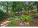 Beautiful landscaping with mature trees, ground cover, and decorative stone accents along a wooden fence at 8045 Depford Way, Cumming, GA 30041