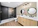 Modern bathroom features a double vanity, sleek lighting, round mirrors, and glass enclosed shower with dark accent tile at 1111 Edgefield Sw Dr, Atlanta, GA 30310