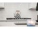 Close-up of gas range with decorative tea kettle on stovetop and subway tile backsplash at 3 Hundley Ln, Roswell, GA 30076