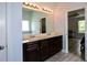 Bathroom with double sinks, vanity with dark wood cabinets, framed mirror, and view into bedroom at 917 Revere Way, Hampton, GA 30228