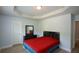 Bedroom with a dark dresser and bed with red comforter featuring a window and wood-look flooring at 917 Revere Way, Hampton, GA 30228