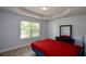 Bedroom with window and wood-look flooring; features dark dresser and bed with red comforter at 917 Revere Way, Hampton, GA 30228