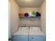 A bright laundry room with washer and dryer on the floor and storage space on the shelf above at 917 Revere Way, Hampton, GA 30228