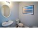 This powder room features an oval mirror over a pedestal sink, a toilet, and a beach-themed picture on the wall at 917 Revere Way, Hampton, GA 30228