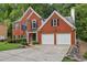 A view of a charming two-story brick home with a two-car garage, and basketball hoop in driveway at 135 Clubhouse Nw Dr, Kennesaw, GA 30144