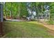 Large, grassy yard with a fire pit area, a tool shed, and mature trees surrounding the property at 135 Clubhouse Nw Dr, Kennesaw, GA 30144