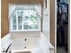 Bathroom featuring a soaking tub with a large window and a glimpse into a well-organized closet at 21 Picketts Ridge Ln, Acworth, GA 30101