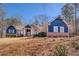 Inviting exterior of a brick and blue home with dormers, front yard, and mature trees under a sunny blue sky at 410 Fitzgerald Ln, Fayetteville, GA 30215