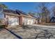 Attached three car garage with brick facade and large driveway, surrounded by trees at 410 Fitzgerald Ln, Fayetteville, GA 30215